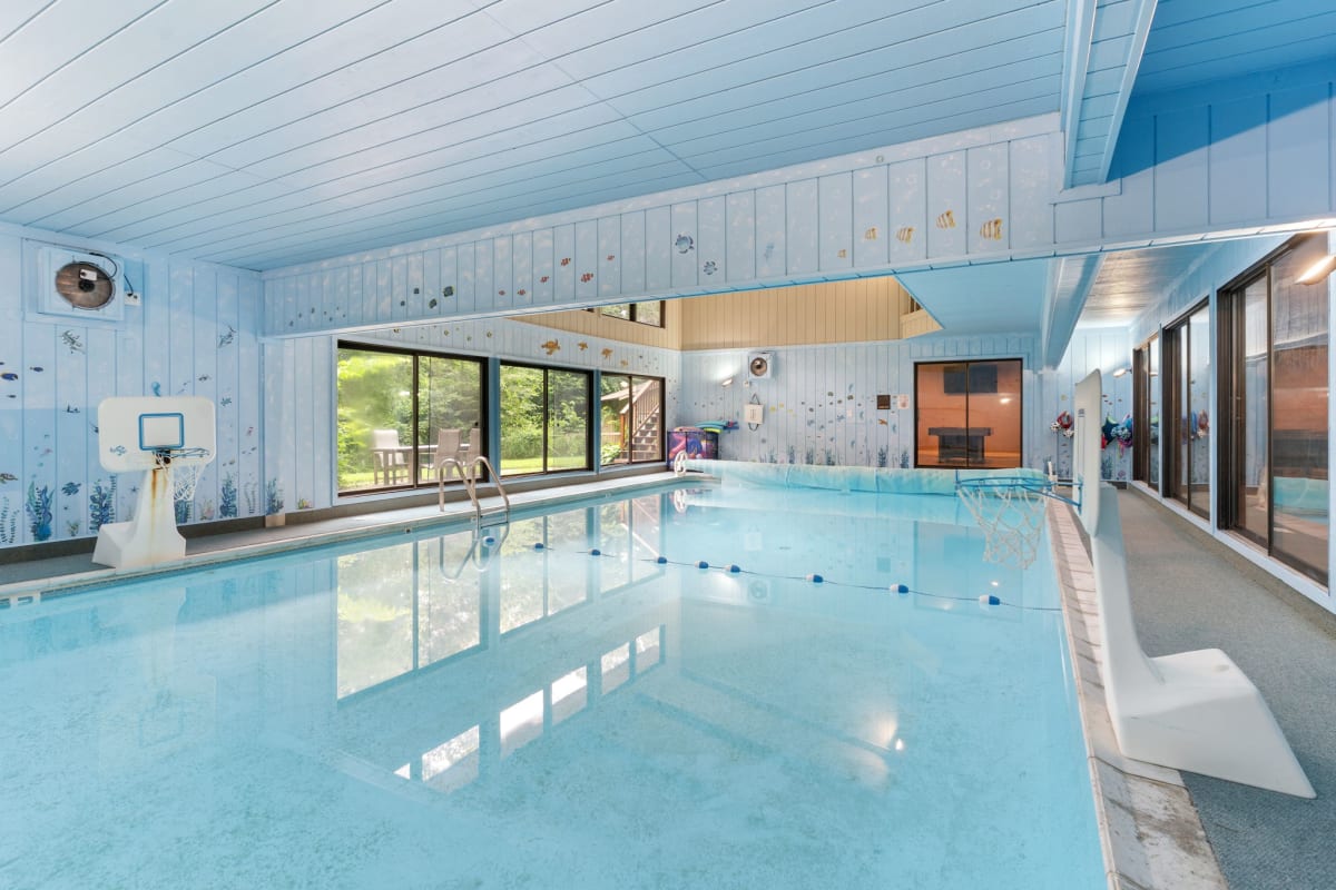 Dive into your private indoor pool sanctuary, where crystal-clear waters reflect soaring ceilings and garden views create the perfect aquatic escape.
