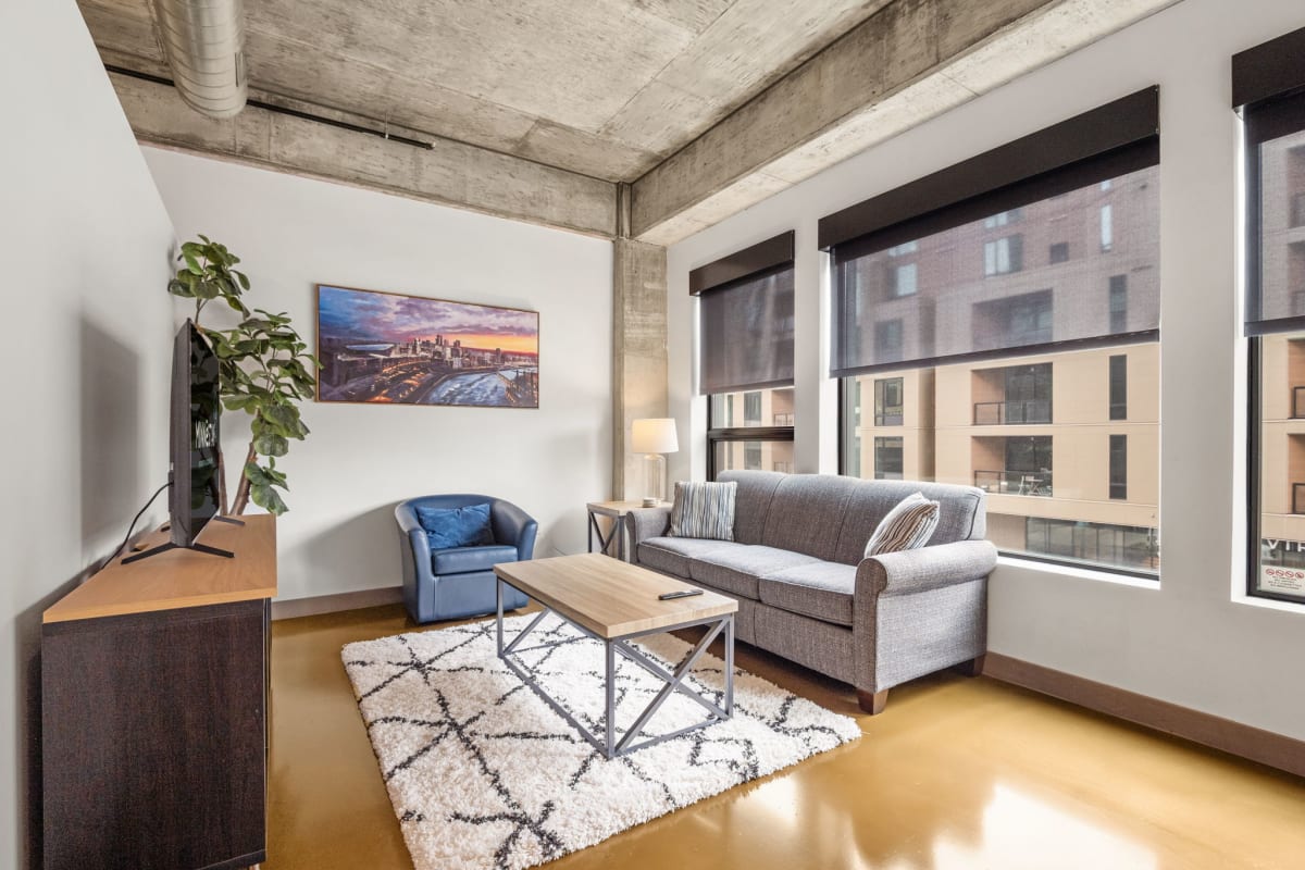 Unwind in your stylish living room where exposed concrete beams meet modern comfort, offering city views from expansive windows.