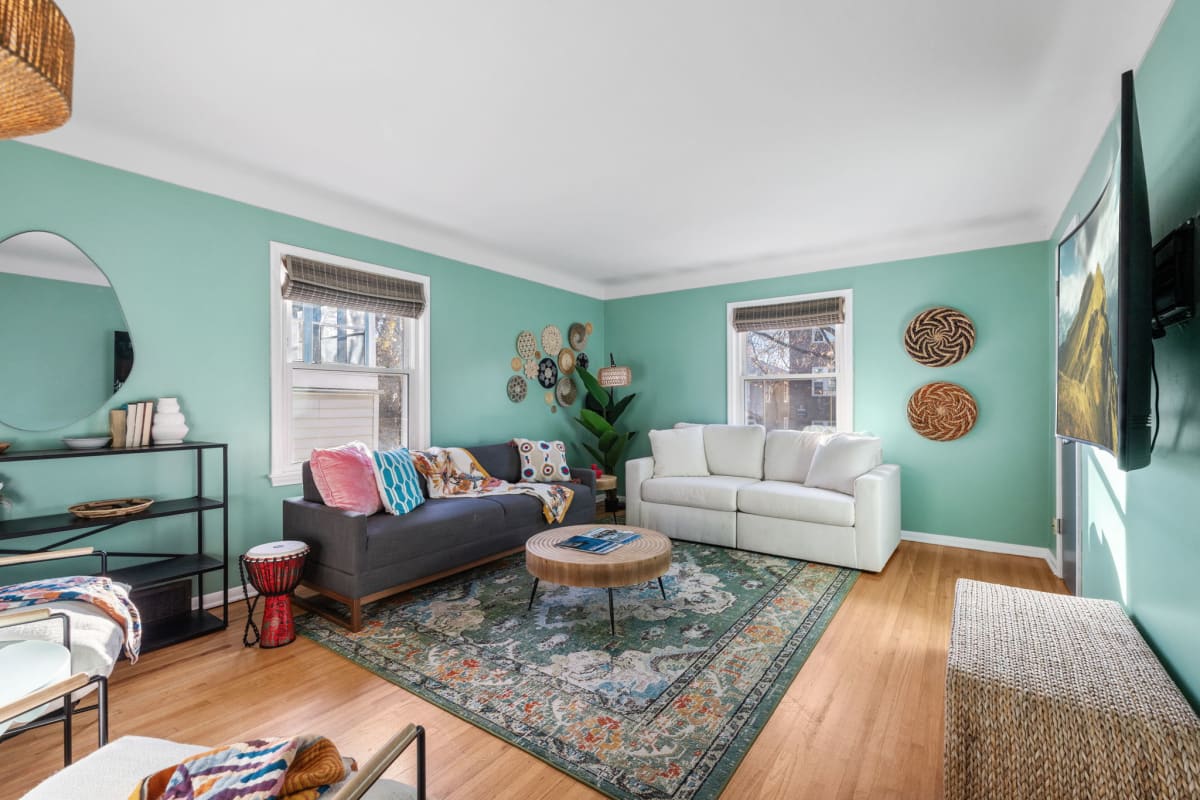 Unwind in your bright living room where mint walls and warm wood floors create the perfect backdrop for relaxation.