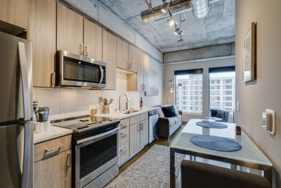 A modern kitchen with stainless steel appliances and a cozy living area featuring a gray sofa.