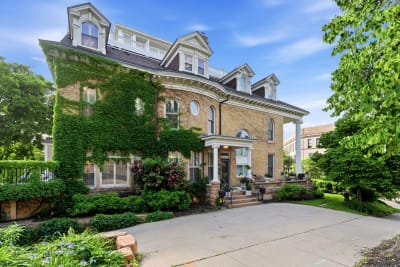 A historic brick home with ivy-covered walls, featuring elegant architectural details and surrounded by gardens.