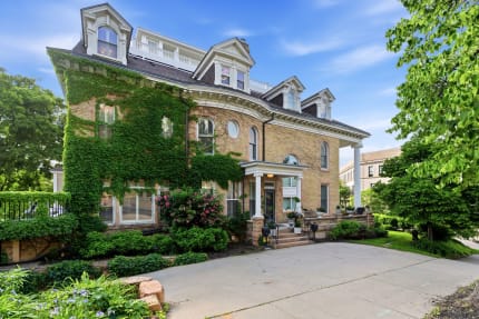 A historic brick home with ivy-covered walls, featuring elegant architectural details and surrounded by gardens.
