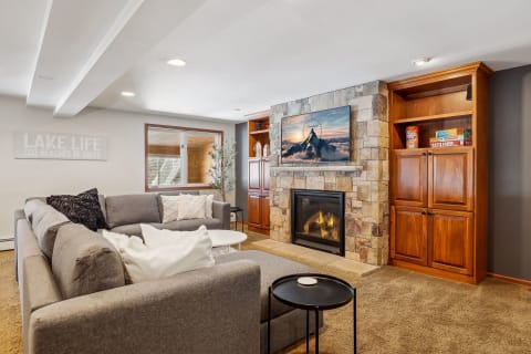 Spacious living room with a gray sofa, fireplace, and wooden cabinetry, decorated for relaxation.