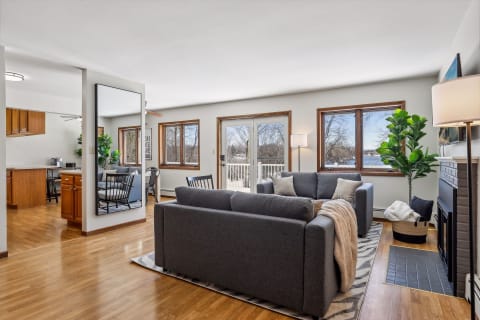 A spacious living room with gray sofas, large windows, and views of a winter landscape.