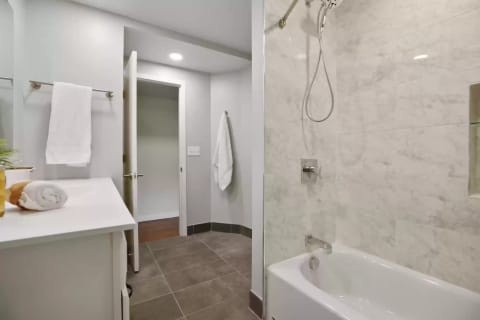 A well-designed bathroom featuring a bathtub, marble tiles, and neatly arranged towels.