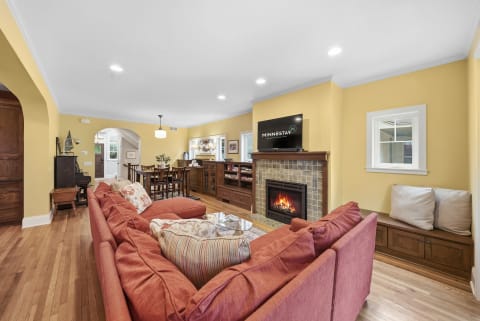 A warm living room featuring a red sofa, wooden furniture, and a fireplace, creating a cozy atmosphere.