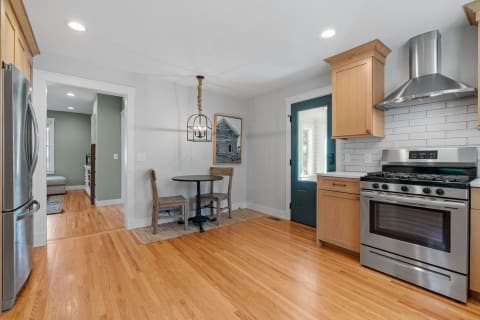 An inviting kitchen featuring hardwood floors, stainless steel appliances, and a teal door.