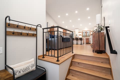 Interior view of a modern foyer with a bench and staircase leading to a living area.