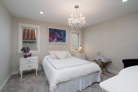 Decorated bedroom featuring a bed, chandelier, and colorful artwork.