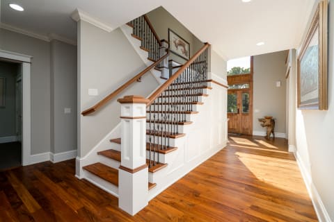 Interior view of a modern entrance with a staircase and wooden flooring.