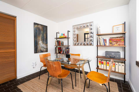 Modern dining space with glass table and abstract wall art.