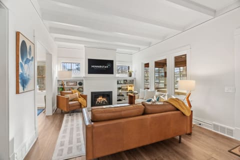 Stylish living room with leather seating, fireplace, and large windows letting in natural light.