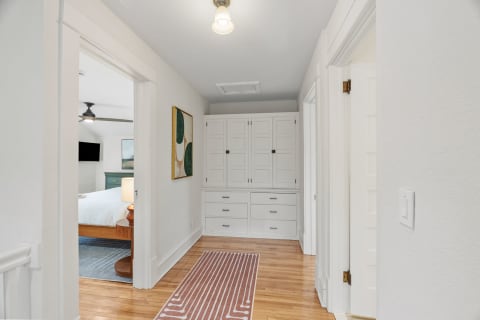A bright hallway featuring hardwood floors and built-in storage with a modern design and a touch of artwork.