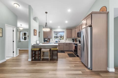 Modern kitchen with light brown cabinets, stainless steel appliances, and wooden flooring.