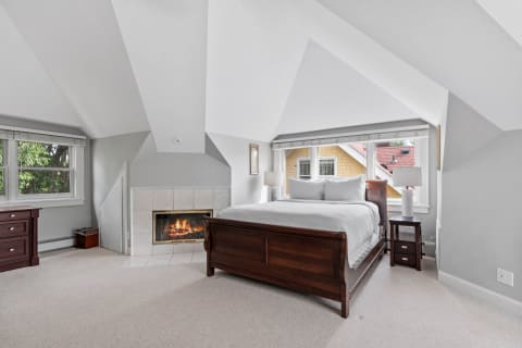 Cozy bedroom with a sleigh bed, fireplace, and large window.