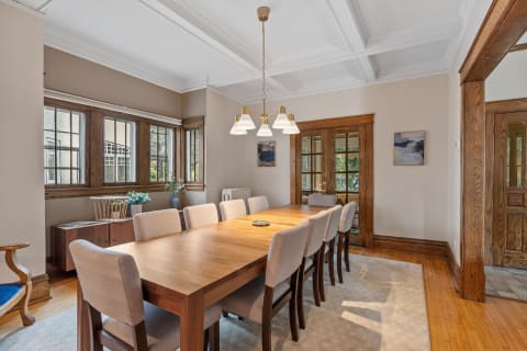 Bright dining room with a wooden table and upholstered chairs.