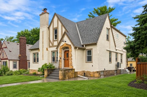 Tudor-style home with a stone porch and well-kept lawn in a friendly neighborhood.