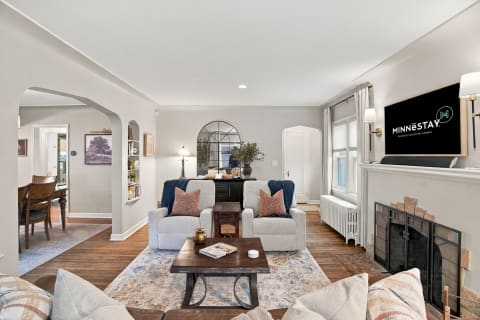 Cozy living room with plush gray seating, wood accents, and a fireplace, inviting relaxation.