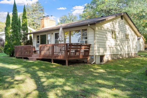 A single-story house with a deck and surrounding greenery.