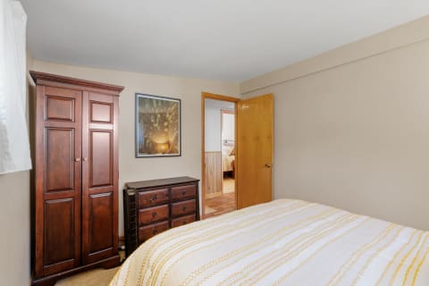 Interior view of a cozy bedroom with wooden furniture and a forest-themed picture.