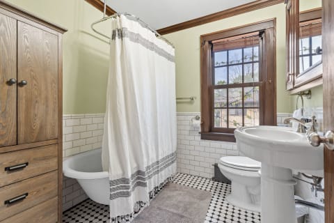 A cozy bathroom featuring a shower curtain, modern bathtub, and natural light from a window.