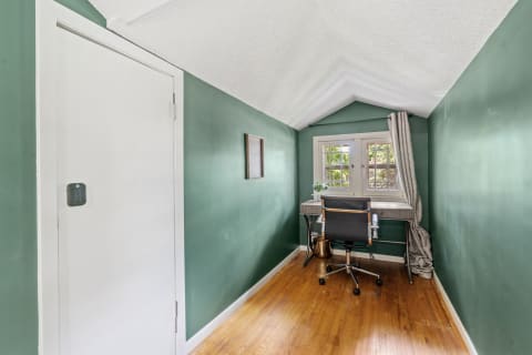 Cozy home office with sloped ceiling, green walls, and modern furnishings.