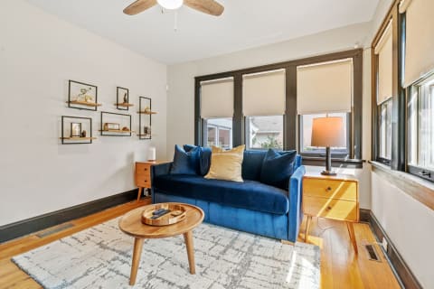 A modern living room featuring a blue sofa, wooden furniture, and decorative shelves.