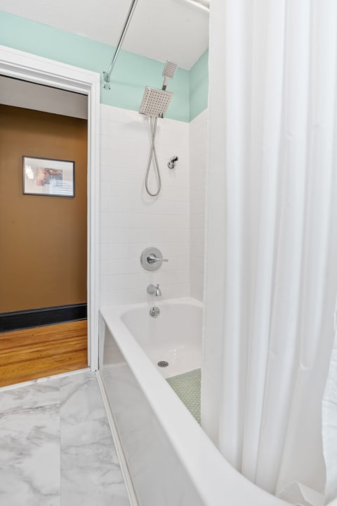 A stylish bathroom with a white bathtub, shower, and outdoor view.