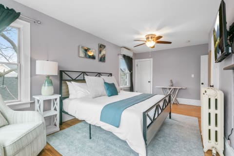 A modern bedroom with gray walls, a metal bed frame, and turquoise accents.