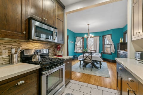 Interior view of a modern kitchen leading to a dining area with turquoise walls.