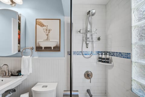 Elegant bathroom with blue walls, white tile, and giraffe artwork, featuring modern fixtures and decor.