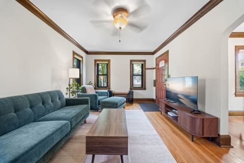 Inviting living room with teal furniture, hardwood floors, and natural light from large windows.