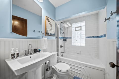 A beautifully designed bathroom with blue walls, white subway tiles, and modern fixtures, featuring a whimsical giraffe art piece.