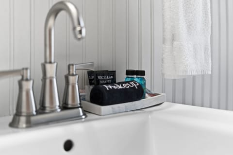 Sleek bathroom setup featuring a stainless steel faucet, neatly arranged toiletries, and a plush towel with 'Makeup' embroidered on it.