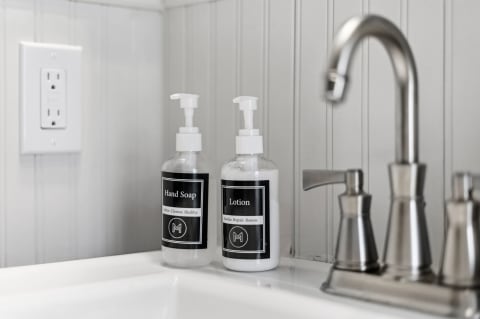 Stylish sink featuring hand soap and lotion in sleek dispensers.
