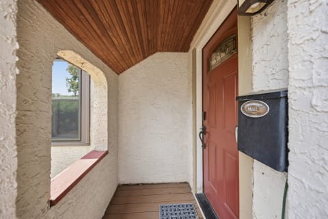 A cozy entryway with a burgundy front door and textured white walls.