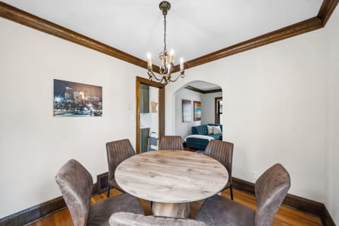 A rustic dining table with velvet chairs and warm wooden accents, featuring a chandelier and urban artwork on the wall.