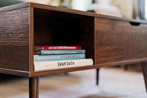 A mid-century modern entertainment center with books on shelves and a sleek storage drawer.