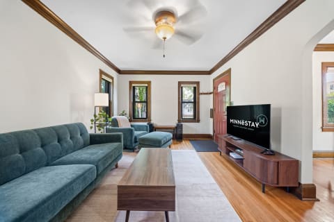 A stylish living room featuring teal furnishings, hardwood floors, and elegant wood trim, creating a cozy retreat.
