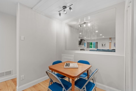 A small dining area with a wooden table and blue chairs, featuring a board game on the table.