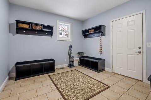 A tidy mudroom with black storage, a vacuum cleaner, and a decorative rug.
