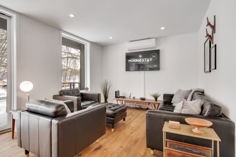 Stylish living room with leather sofas, a modern lamp, and large windows.