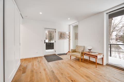 Modern entryway with wooden floors, beige chair, and stylish decor.