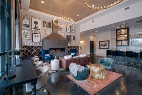 A cozy communal lounge featuring velvet seating, a fireplace, and an art-filled wall, designed for relaxation.