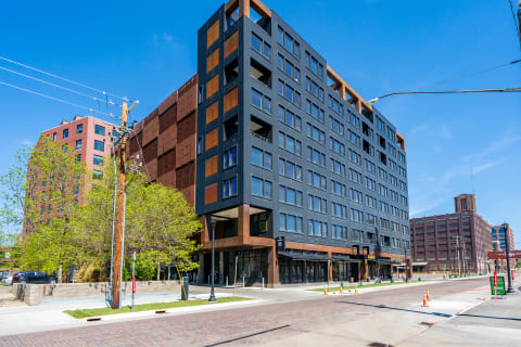 Modern mixed-use building with large windows and retail spaces in an urban setting.