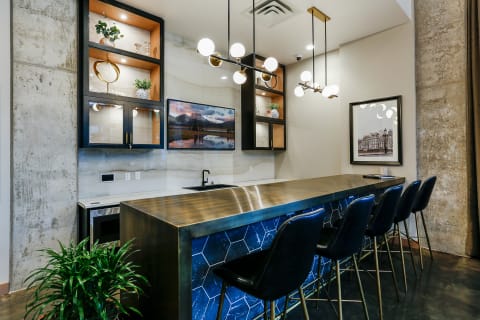 Modern communal kitchen island with polished metal countertop and stylish pendant lighting.