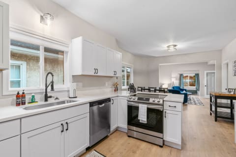 Modern kitchen with white cabinets and a stainless steel stove in an open-plan space.