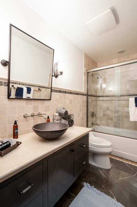Modern bathroom featuring a dark vanity, unique sink, and glass shower enclosure.