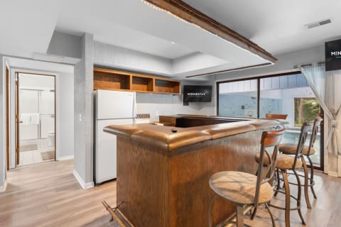Interior of a modern kitchen with a bar area, refrigerator, and view of outdoor space.