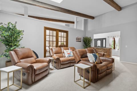 A cozy living room featuring brown recliner chairs, white side tables, and a lush green plant.